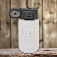A matte white 12 oz Kodiak Coolers Custom Kids Water Bottle with black lid, engraved with "YOUR LOGO ENGRAVED HERE," sits on a wooden surface. Perfect for personalized logos or names—special Black Friday sale volume pricing, limited time!.