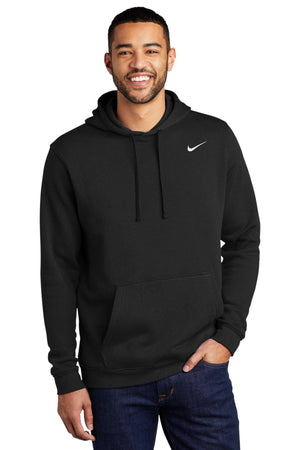 A person in a Nike Club Fleece Pullover Hoodie Sweatshirt CJ1611, featuring a small white swoosh logo, wearing jeans and smiling, stands against a plain white background.