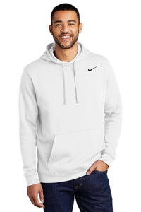A person wearing a white Nike Club Fleece Pullover Hoodie Sweatshirt CJ1611 with a small embroidered Swoosh on the left chest, standing with one hand in the hoodie pocket and smiling.