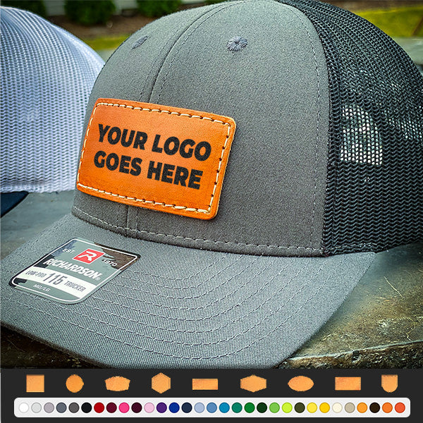 The Richardson 112 Snapback Trucker Cap by Richardson features a gray and black design with a blank leather patch for your logo, cotton/poly front, mesh back, snapback closure, and is shown next to another hat displaying patch and color options.