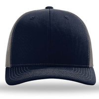 The Richardson 112 Snapback Trucker Cap by Richardson is a navy blue baseball hat with gray mesh side panels and white stitching, shown from the front. Custom embroidery available.