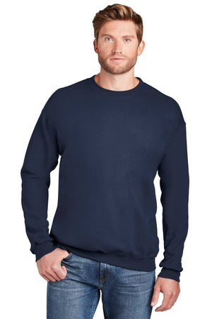 A man wearing a Hanes Ultimate 100% Cotton Crewneck Sweatshirt F260 in navy blue and blue jeans stands facing forward with one hand in his pocket.