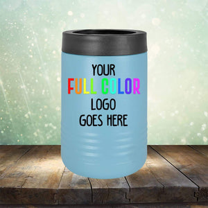 A blue insulated can cooler with a black top, showcasing the text "YOUR FULL COLOR LOGO GOES HERE." The backdrop is a sparkling light green with a wooden surface beneath. Perfect for tumblers or coffee mugs, the Custom UV Printed Drinkware - ONE TIME SPECIAL OFFER from Kodiak Coolers features premium engraving options to personalize your branding.