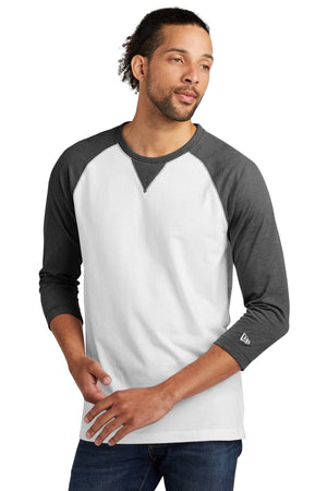 A person wearing a New Era Cotton Blend 3/4-Sleeve Baseball Raglan T-Shirt NEA121, featuring a white and gray design, and jeans is standing against a plain background.