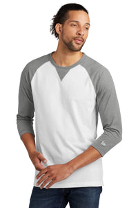 A person wearing a New Era Cotton Blend 3/4-Sleeve Baseball Raglan T-Shirt, NEA121, in white and gray, with jeans.