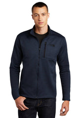Man in a navy blue The North Face NF0A47F5 Full-Zip Fleece Jacket made of recycled polyester and technical stretch fleece, standing with a neutral expression.