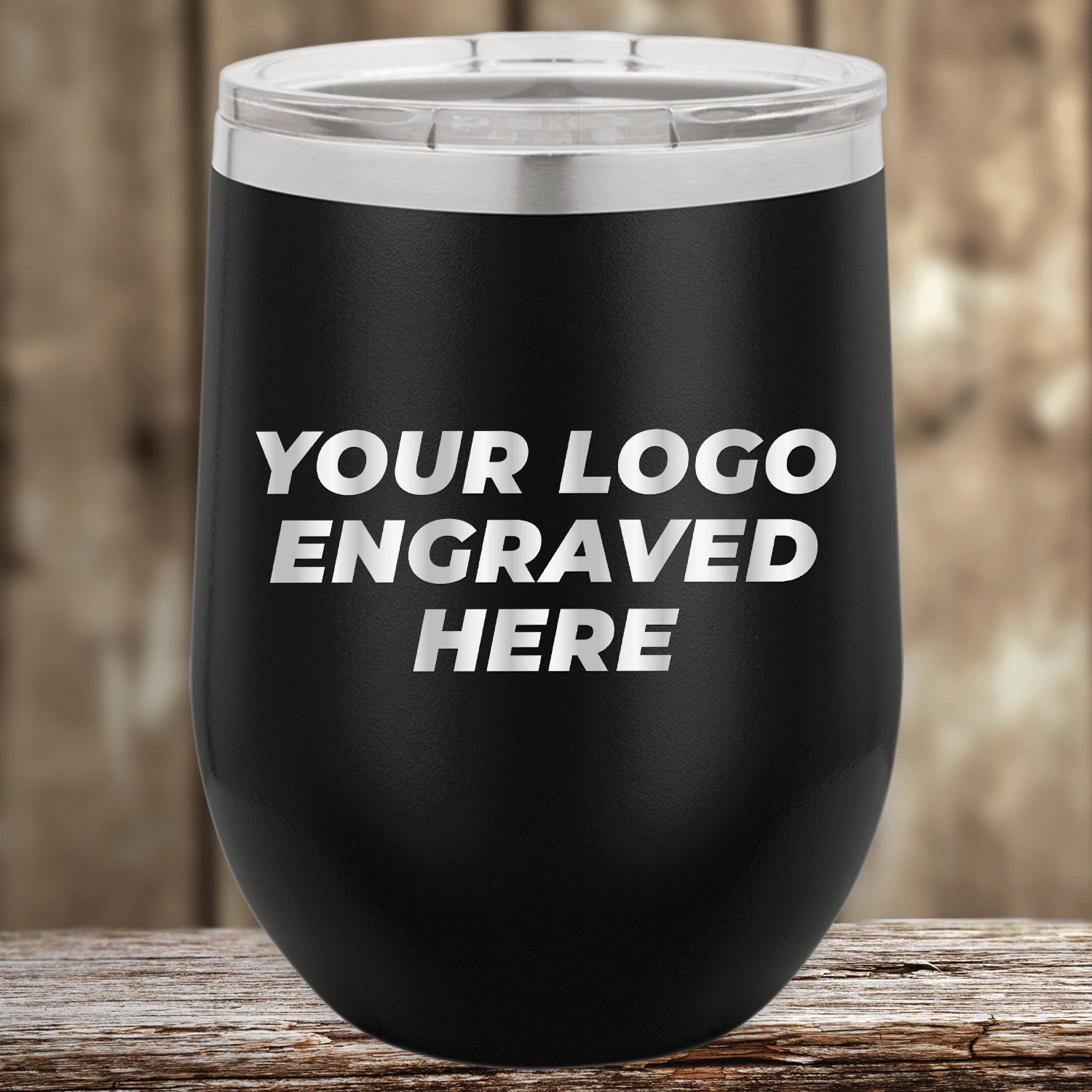 A black Kodiak Coolers Custom 12 oz Stemless Wine Cup with your logo engraved and clear lid sits on wood—ideal as a stylish custom mug or promotional gift. Bulk wholesale pricing available.