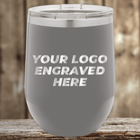 The Kodiak Coolers Realtor Closing Gifts for Clients tumbler features your custom company logo engraved on gray insulated drinkware with a clear lid, perfect as stylish promotional gifts, displayed on a wooden surface.