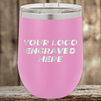 A pink stainless steel tumbler with clear lid by Kodiak Coolers, engraved with "YOUR LOGO ENGRAVED HERE," set on wood—perfect as a Realtor closing gift or for custom company logo drinkware.