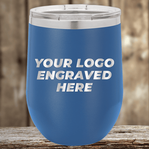 A blue insulated tumbler by Kodiak Coolers with a silver lid, engraved with your custom company logo, rests on a wooden surface—perfect as Realtor closing gifts for clients and promotional drinkware to showcase your brand.