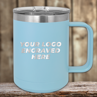 A light blue Kodiak Coolers insulated mug with a clear lid and your custom company logo engraved sits on a wooden surface—an ideal Realtor closing gift for clients.