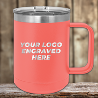 A coral Kodiak Coolers insulated mug with handle and clear lid, custom engraved with your company logo—perfect as a Realtor closing gift for clients or a unique promotional item. Shown on a wooden surface with a blurred wood background.