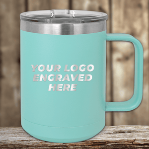 A turquoise Kodiak Coolers 15 oz insulated coffee mug with a handle sits on a wooden surface, featuring an engraved logo text—ideal for a personalized gift.