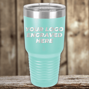 A light blue Kodiak Coolers tumbler with a clear lid rests on wood, featuring “Your Custom Company Logo Engraved” in white—the ideal Realtor closing gift for clients from the Realtor Closing Gifts for Clients collection.