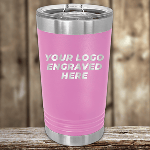 A pink stainless steel tumbler by Kodiak Coolers with a clear lid and your custom company logo engraved sits on a wooden surface—perfect as a Realtor closing gift and stylish promotional drinkware for showcasing your brand.