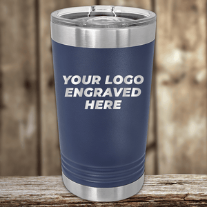 A blue insulated tumbler by Kodiak Coolers sits on a wooden surface, featuring "Your Custom Company Logo Engraved"—an ideal Realtor closing gift or promotional drinkware for clients.