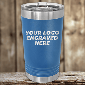 The Kodiak Coolers Realtor Closing Gifts for Clients tumbler features a blue insulated design with a clear lid and your custom company logo engraved on the front—perfect branded drinkware for client gifts, shown on a wooden surface with a blurred wood background.