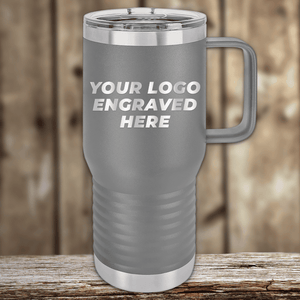 Gray insulated travel mug by Kodiak Coolers with a handle and clear plastic lid, featuring your custom company logo—ideal as Realtor closing gifts or promotional drinkware—displayed on wood with a “YOUR LOGO ENGRAVED HERE” design.