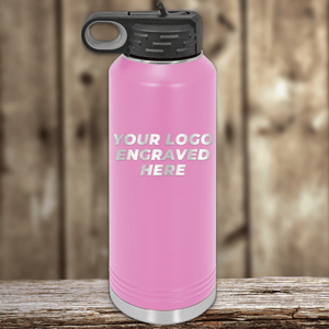 A pink Kodiak Coolers insulated water bottle with a black lid, shown upright on wood, features “Your Custom Company Logo Engraved” on the front—ideal as a Realtor closing gift or unique promotional drinkware for clients.