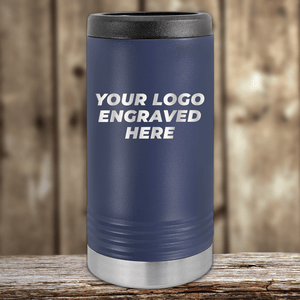 The Kodiak Coolers Realtor Closing Gifts for Clients tumbler features your custom company logo engraved, with a navy blue body, black lid, and silver bottom. It sits on a wooden surface against a blurred wood background.
