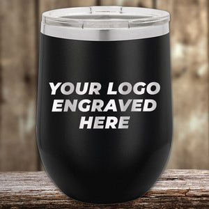 A black travel mug by Kodiak Coolers rests on a wooden surface with "Your Logo Engraved Here." This custom engraved drinkware is perfect for personalization, featuring one side logo included with no setup fee. A $250 minimum order is required for the Presidents Day sale.