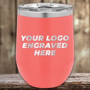 A coral-pink Kodiak Coolers insulated tumbler with a customizable engraving area for an engraved logo, displayed on a wooden surface.