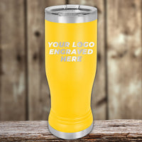 A yellow Kodiak Coolers 14 oz custom pilsner glass with a stainless steel lid and base, engraved with "YOUR LOGO HERE," sits on wood—perfect for highlighting Black Friday sale volume pricing on personalized tumblers.