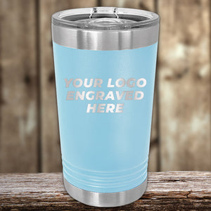 A blue Custom Pint Tumbler 16 oz with your Logo or Design Engraved displayed on a wooden surface by Kodiak Coolers.