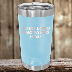 A Kodiak Coolers Custom Pint Glass 16 oz with your logo engraved sits on a wooden surface with a clear lid, showcasing personalized drinkware—get them now during the special Black Friday Sale volume pricing for a limited time!.