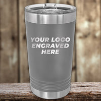 A Kodiak Coolers custom engraved stainless steel tumbler, ideal for displaying your logo without a setup fee, rests elegantly on rustic wood with a blurred wooden backdrop. Enjoy this special for Presidents Day with no setup fee and only a $250 minimum order required.