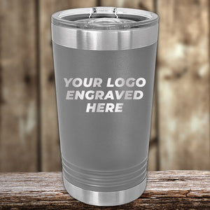 A Kodiak Coolers custom engraved stainless steel tumbler, ideal for displaying your logo without a setup fee, rests elegantly on rustic wood with a blurred wooden backdrop. Enjoy this special for Presidents Day with no setup fee and only a $250 minimum order required.