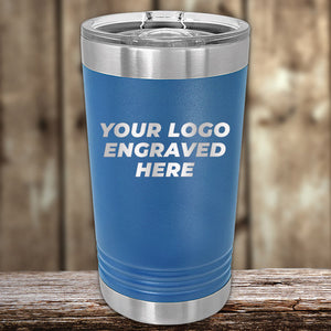 A blue insulated tumbler with a silver lid from Kodiak Coolers, engraved with "YOUR LOGO ENGRAVED HERE," sits on wood. This custom drinkware combines style and durability, ideal for laser-engraved logos. No setup fee; minimal order $250 during Presidents Day sale.