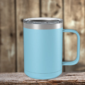A blue insulated stainless steel Kodiak Coolers coffee mug sits on a wooden table.