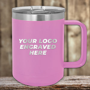 This Kodiak Coolers 15 oz pink insulated mug with a clear lid, perfect for keeping beverages hot and fresh, features "YOUR LOGO ENGRAVED HERE" for custom designs. It rests seamlessly on a wooden surface and is available at special bulk wholesale pricing.