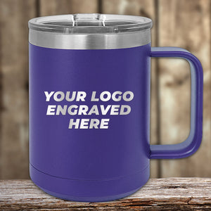 The Kodiak Coolers Bulk 15 oz Custom Coffee Mug in blue features a stainless steel design with a silver lid and handle. "YOUR LOGO ENGRAVED HERE" is laser-engraved on the side, making it perfect for custom mugs. It's showcased on a wooden surface with a blurred background, ideal for wholesale buyers.