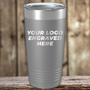 Stainless steel tumbler with customizable engraving space, ideal as a corporate promotional gift, displayed on a wooden surface. Bulk Custom Tumblers 20 oz with your Logo or Design Engraved - Special Bulk Wholesale Volume Pricing RAJAT by Kodiak Coolers.