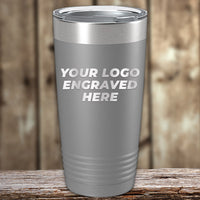 Gray Kodiak Coolers insulated tumbler showcasing "Your Logo Engraved Here" with a laser-engraved logo on a wooden surface, and a blurred wooden backdrop. Ideal for custom engraved drinkware enthusiasts during the special Presidents Day Sale with no setup fee.