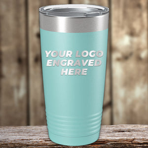 A teal Engraved Custom Logo Drinkware tumbler by Kodiak Coolers with a stainless steel lid, "YOUR LOGO ENGRAVED HERE" on front. Single side engraving and bulk pricing available. Wooden background shown. Perfect for custom or personalized mugs.