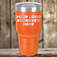 Kodiak Coolers Engraved Custom Logo Drinkware with single side engraving, shown in orange with a clear lid and "YOUR LOGO ENGRAVED HERE"—ideal for bulk custom mugs—displayed on a wooden surface with a blurred wood background.