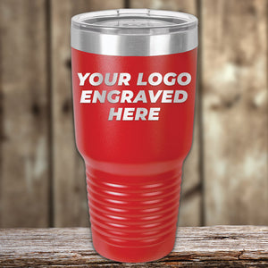 A red Kodiak Coolers tumbler with a clear lid sits on a wooden surface, displaying "YOUR LOGO ENGRAVED HERE"—the Engraved Custom Logo Drinkware offers single side engraving and bulk tiered pricing for stylish personalized mugs.