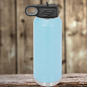 A light blue Kodiak Coolers insulated stainless steel water bottle with a black cap, placed on a wooden surface against a blurred wooden background.