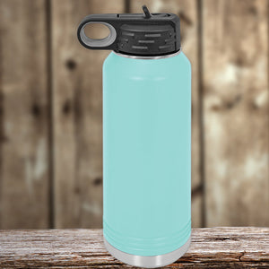 Kodiak Coolers Aqua blue insulated stainless steel water bottle with a black flip-top lid, sitting on a wooden surface against a blurred wooden background.