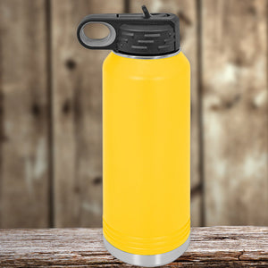 Yellow insulated stainless steel water bottle with a black cap, sitting on a wooden surface against a blurred wooden background by Kodiak Coolers.