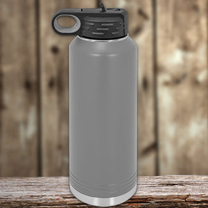 Insulated stainless steel Kodiak Coolers water bottle with handle on wooden surface against a wooden backdrop.