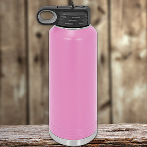 A pink Kodiak Coolers Custom Water Bottle 40 oz with your Logo or Design Engraved on a wooden surface with a blurred background.