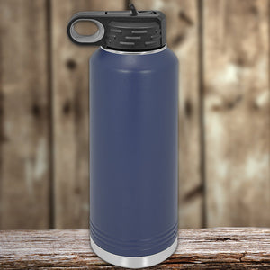 A blue insulated stainless steel Custom Water Bottles 40 oz with your Logo or Design Engraved from Kodiak Coolers, with a handle on the lid, placed on a wooden surface against a blurred wooden backdrop.