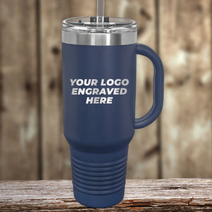 A blue travel mug from Kodiak Coolers with a handle and silver lid sits on a wooden surface, showcasing "YOUR LOGO ENGRAVED HERE." Ideal for those wanting custom tumblers with laser engraving. No setup fee; 1 side logo included in price. $250 minimum order needed for Presidents Day sale.