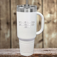 A Kodiak Coolers custom engraved white travel mug with a handle and straw lid sits on a wooden surface. The tumbler reads, "YOUR LOGO ENGRAVED HERE." Perfect for those seeking wholesale pricing, it requires a $250 minimal order during the Presidents Day Sale.