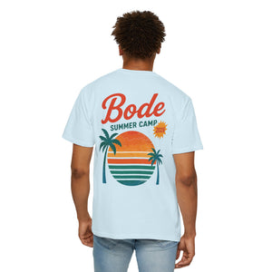 Man wearing a light blue Printify BODE Summer Camp T-Shirt 2026 — "Throwback Sunset" (Unisex Comfort Colors 1717), featuring a sunset and palm trees graphic with "Bode Summer Camp 2024" on the back.