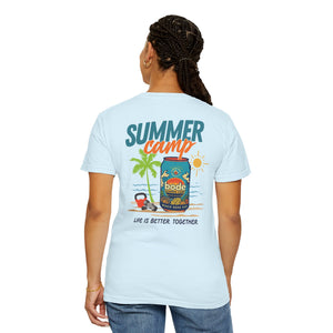 A person wears the BODE Summer Camp T-Shirt 2026 by Printify, a light blue heavyweight cotton tee featuring palm trees, vintage beach graphics, and "SUMMER camp" and "Life's Better Together" on the back.